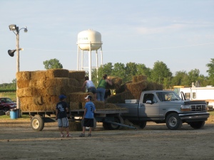 A team of red neck racers load bales of hay onto the back of their pick-up truck.